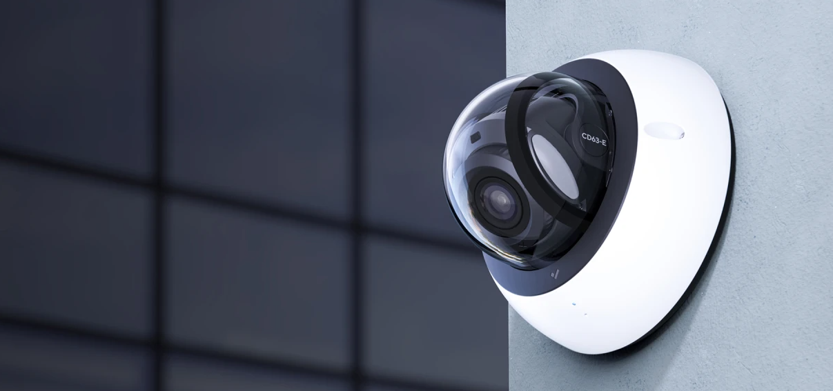 Verkada CD63-E dome security camera mounted on a commercial building exterior, monitoring a glass office property.