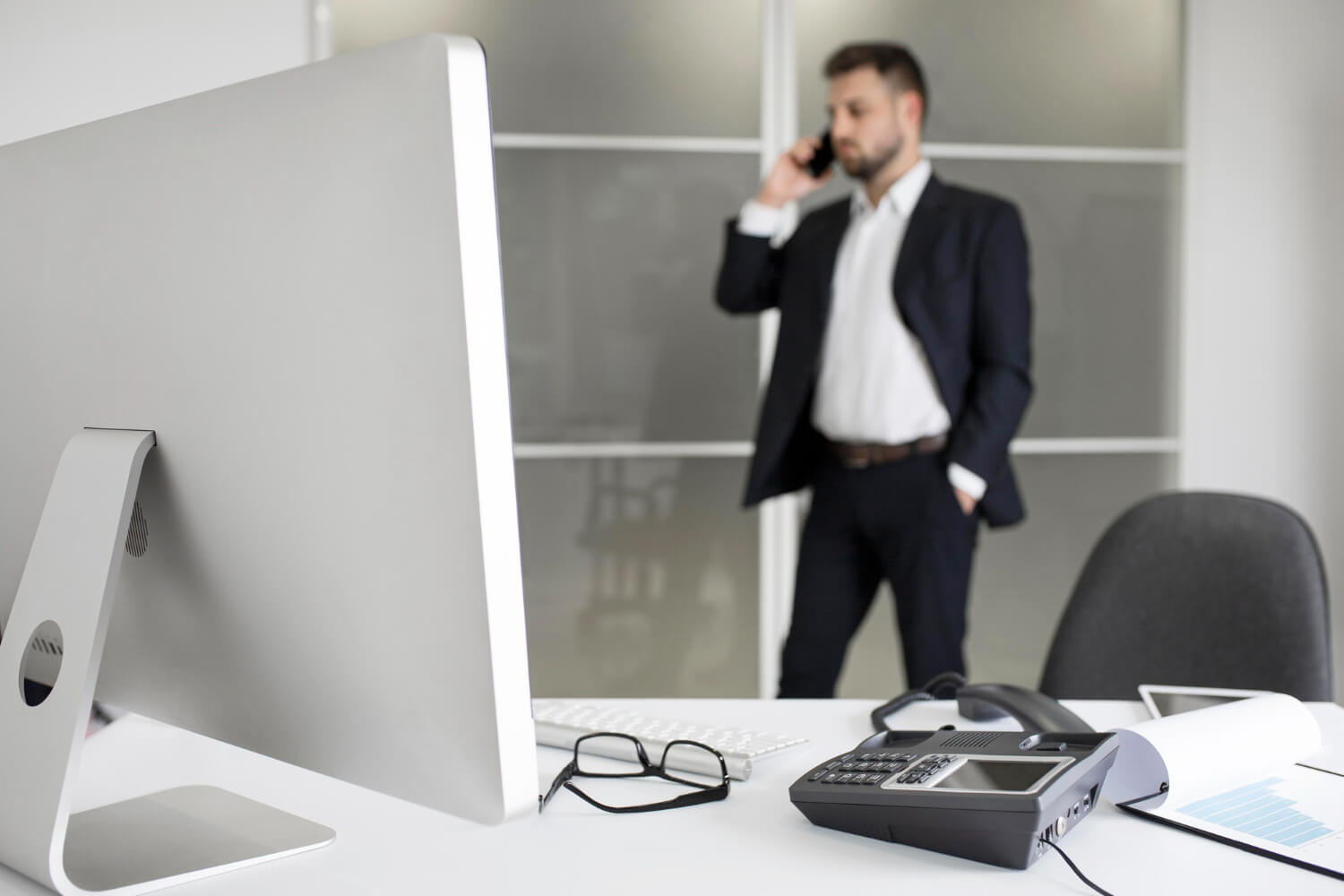 Businessman in Albuquerque office reviewing Best RingCentral Alternatives in Albuquerque with Wired VoIP phone system.